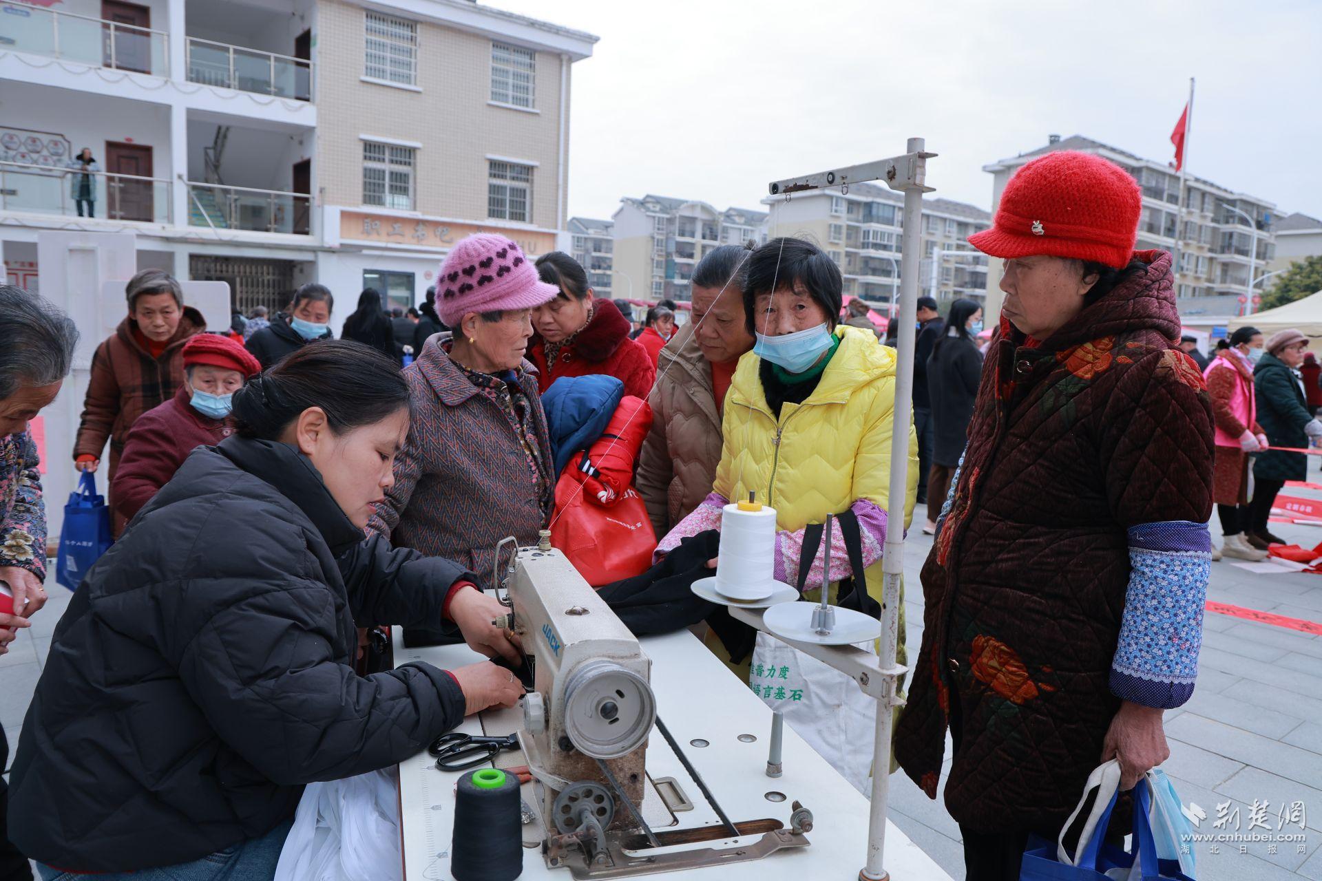 衣物縫補(bǔ)攤前，志愿者飛針走線為居民修補(bǔ)破損衣物.jpg.jpg